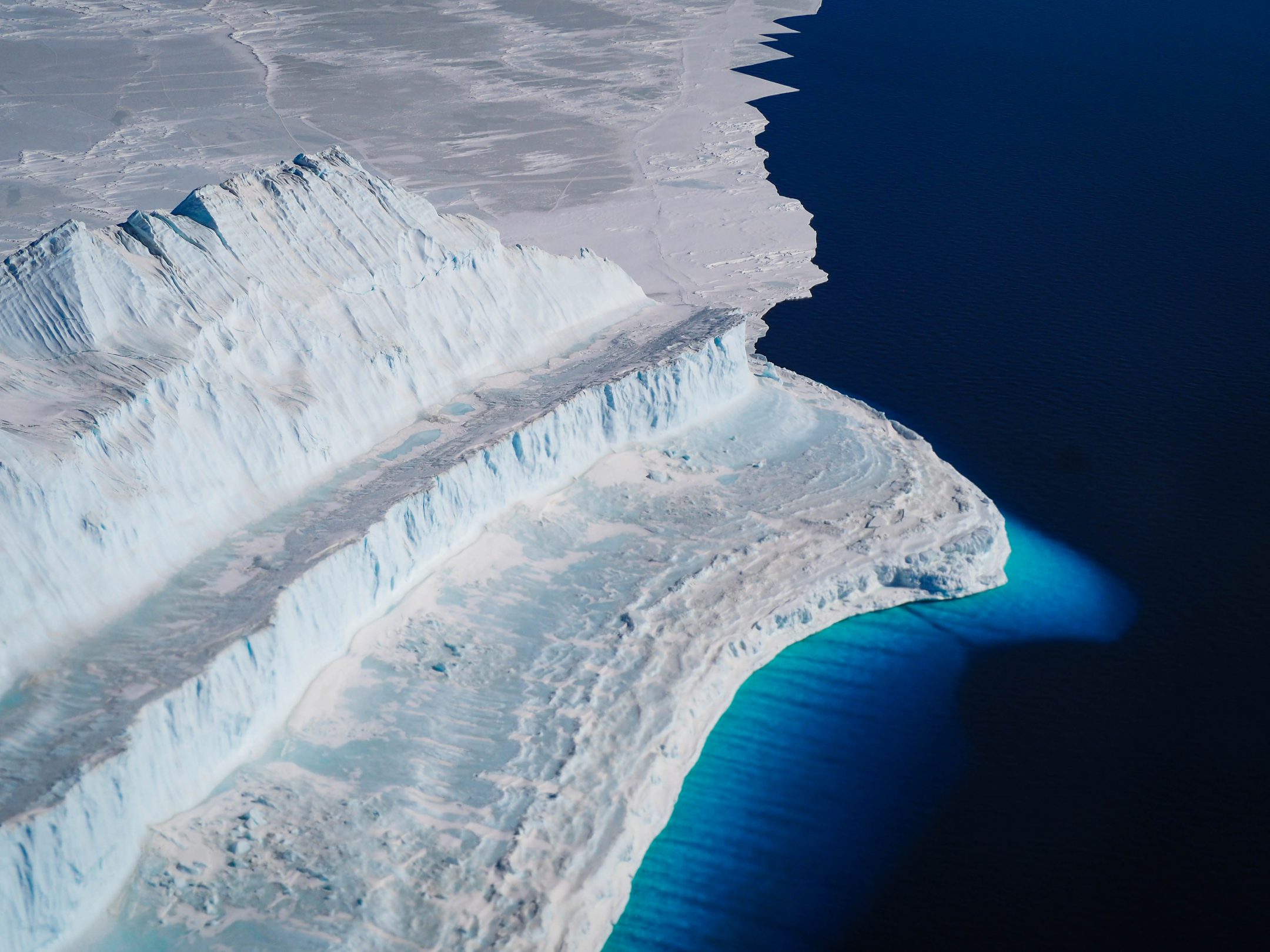 aerial image of polar sea ice bridge with white ice and dark blue waters